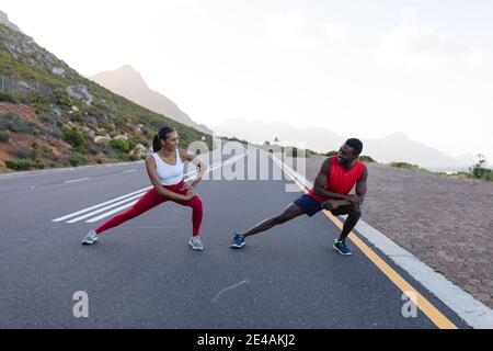 Adatta la coppia afroamericana in abbigliamento sportivo che si estende su una costa strada Foto Stock