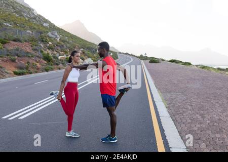 Adatta la coppia afroamericana in abbigliamento sportivo che si estende su una costa strada Foto Stock