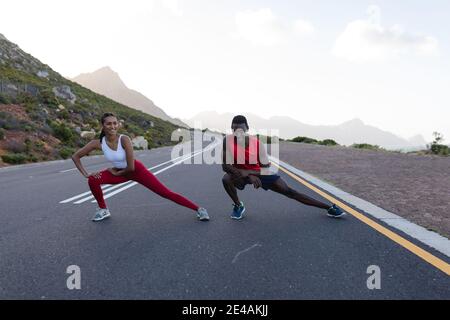 Adatta la coppia afroamericana in abbigliamento sportivo che si estende su una costa strada Foto Stock