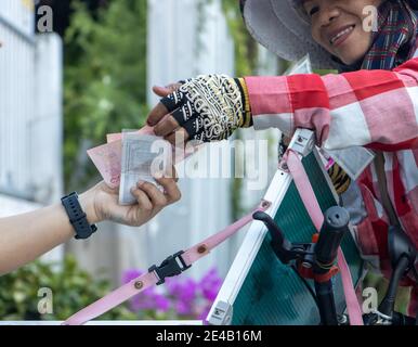 SAMUT PRAKAN, THAILANDIA, 14 marzo 2020, Una venditrice sorridente della lotteria vende il biglietto in una strada Foto Stock