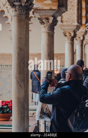 Siviglia, Spagna - 19 gennaio 2020: L'uomo scatta foto del cortile del patio de Maidens all'interno dell'Alcazar di Siviglia, un palazzo reale costruito per la K cristiana Foto Stock