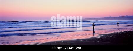 I turisti praticano la pesca a mosca sulla spiaggia al tramonto, Morro Bay, San Luis Obispo County, California, USA Foto Stock
