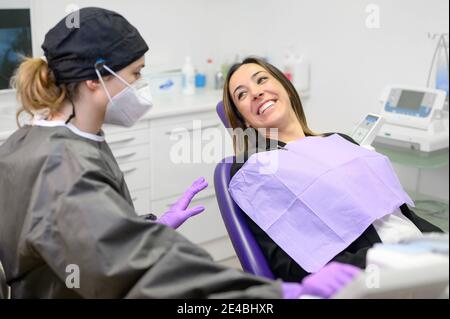 Giovane paziente in visita dentista Office.Beautiful donna seduta in sedia dentale con bocca aperta durante il controllo orale mentre il medico lavora ai denti. Foto di alta qualità Foto Stock