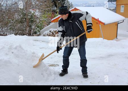 Un uomo libera la neve in inverno da un sentiero Foto Stock