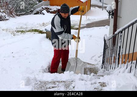 Un uomo libera la neve in inverno da un sentiero Foto Stock