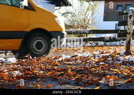 Strade pericolose in autunno e inverno con foglie e neve Foto Stock