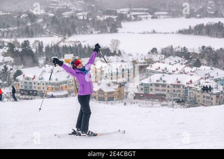Sciatore felice con le armi in su nella felicità alla stazione sciistica di Mont Tremblant, Quebec, Canada. Vista dalla pista da sci. Donna di sport invernali che si diverte all'aperto Foto Stock