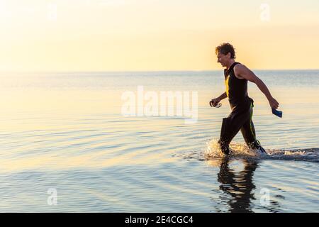 Man 50 Plus FIT, con una muta in mare. Dopo l'allenamento triathlon al mattino nel Mar Baltico Foto Stock