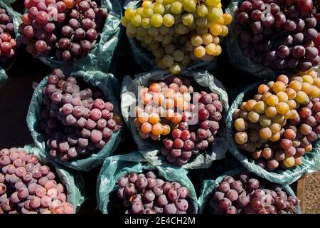 Confezione di uve bianche e rosse/viola/nere, tutte collocate in un mercato dai colori vivaci e dall'aspetto sano. I frutti sono gustosi, pieni di vitamine Foto Stock