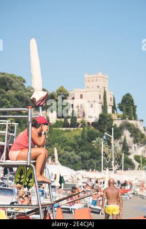 Bagnino in spiaggia seduto in servizio. Italia, finale ligure - 23 agosto 2020. Foto Stock