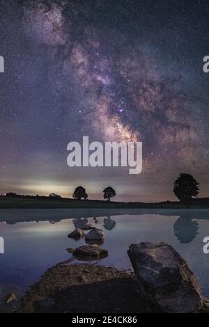 Composizione di un paesaggio da sogno con un lago di Allgäu in primo piano e una Via Lattea su un altopiano di Allgäu. Foto Stock