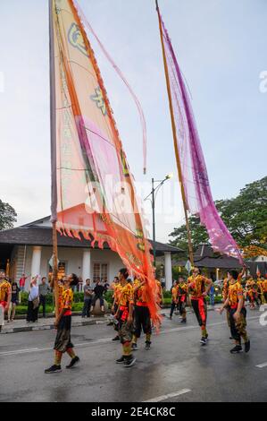 Giovani uomini con bandiere alte a New Years sfilano a Kuching, Malesia Foto Stock