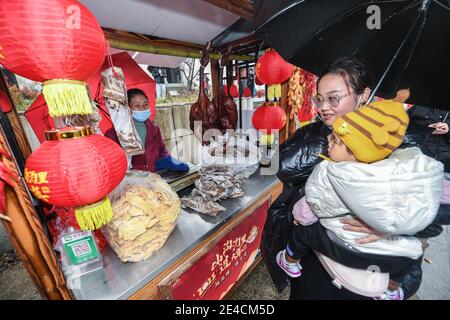 (210123) -- HANGZHOU, 23 gennaio 2021 (Xinhua) -- UN visitatore seleziona le merci di nuovo anno in un mercato di primavera nell'antico villaggio di Maotang nel distretto di Yuhang di Hangzhou, capitale della provincia di Zhejiang della Cina orientale, 22 gennaio 2021. Situato nell'area montagnosa occidentale di Hangzhou, l'antico Villaggio Maotang ha una lunga storia e molti antichi edifici di Huizhou. Con l'avvicinarsi del Festival di primavera, attività popolari come il mercato di primavera, la scrittura di coppie, la produzione di torte di riso appiccicose, il taglio della carta sono tenuti qui per i visitatori di sperimentare le tradizioni cinesi tradizionali. (Xinhua/Xu Yu) Foto Stock