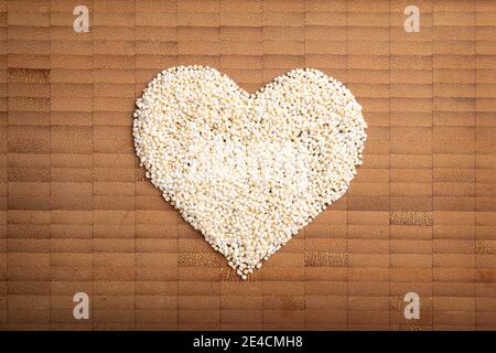 immagine di concetto di amore della forma del cuore fatta di grano amarante su sfondo di legno di bambù Foto Stock