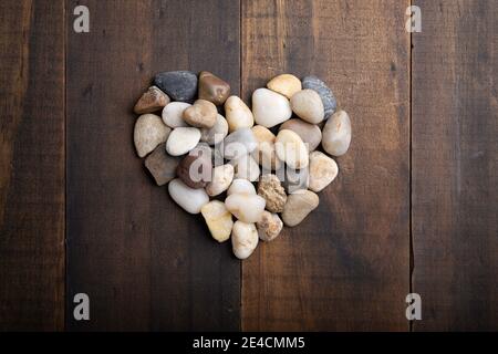 immagine del concetto di amore della forma del cuore fatta di ciottoli rotondi su sfondo di legno Foto Stock