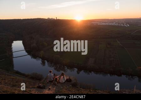 Europa, Germania, Baden-Wuerttemberg, Besigheim, Hessigheim, due giovani donne che hanno un pic-nic sulle rocce nei giardini rocciosi sopra il Neckar al tramonto Foto Stock