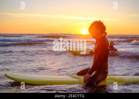 Surfista seduto sul surf in mare Foto Stock
