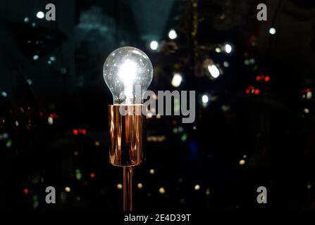 Lampadina brillante con sfondo urbano moderno di notte, che simboleggia le idee luminose nel moderno impulso urbano della vita Foto Stock