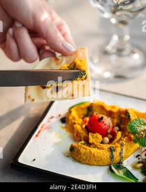 Spalmare l'ummus curry su pita con un coltello Foto Stock