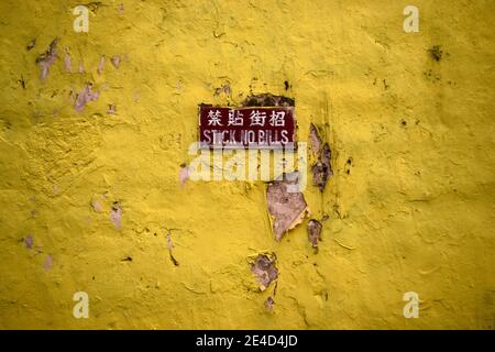 Vecchio muro di grunge giallo con con avviso bastone senza bollette In inglese e cinese Foto Stock