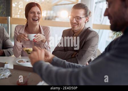 giovani uomini d'affari a pausa, bere caffè, sorridere, ridere, mangiare pizza Foto Stock