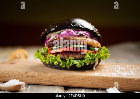 Hamburger nero doppio paty sulla tavola di legno Foto Stock