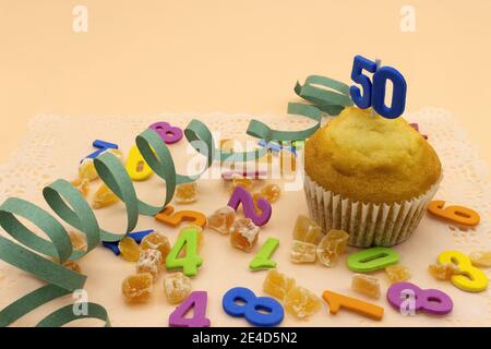 Concetto di compleanno, un cupcake con il numero 50, fagioli di gelatina e numeri di sfondo Foto Stock