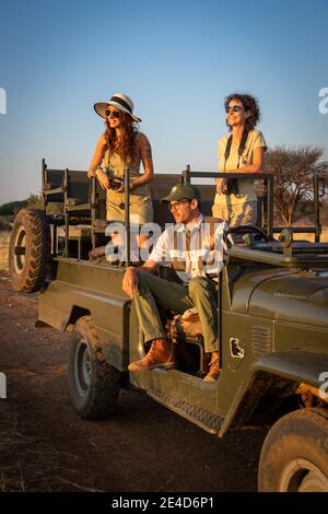 La guida si siede con donne sorridenti in jeep Foto Stock