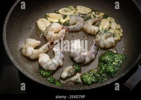 Gamberi freschi o gamberi neri di tigre con olio, aglio e prezzemolo in una padella per un delizioso antipasto mediterraneo, fuoco selezionato, profondità ridotta Foto Stock