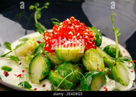 Bruxelles germogli con caviale in una ciotola nera Foto Stock