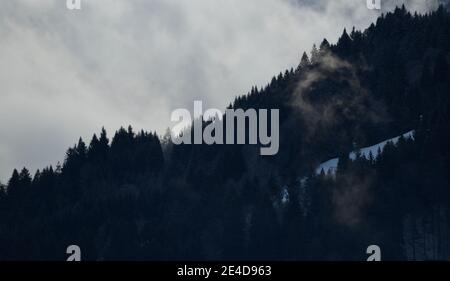 Garmisch Partenkirchen, Germania. 23 gennaio 2021. Le nuvole passano sopra una foresta nelle montagne di Wetterstein. Credit: Angelika Warmuth/dpa/Alamy Live News Foto Stock