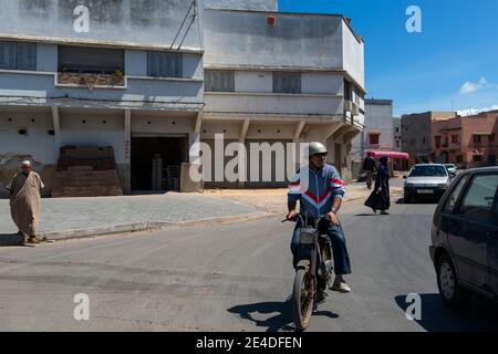 El Jadida, Marocco - 16 aprile 2016: Scena di strada in un quartiere alla periferia della città di El Jadida, con un uomo a cavallo di una moto e pisello Foto Stock