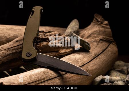 Il coltello è in posizione ripiegata. Coltello curvo. Coltello pieghevole su un log. Vista frontale. Foto Stock