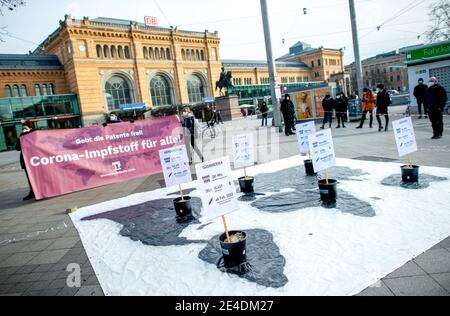 23 gennaio 2021, bassa Sassonia, Hannover: I partecipanti ad una dimostrazione della sinistra interventista sotto lo slogan 'danno i brevetti gratis! Vaccino corona per tutti!' Sono in piedi di fronte alla stazione ferroviaria principale, sul terreno è un banner con i continenti, su di esso sono secchi con segni che dicono quando il rispettivo continente sarà sufficientemente fornito con vaccini Corona. L'occasione è il negoziato dell'Organizzazione mondiale del commercio (OMC) per revocare temporaneamente la protezione brevettuale sui prodotti e sulle tecnologie per contenere la pandemia del Covid 19, come richiesto dall'India e dal Sudafrica. Foto: H Foto Stock