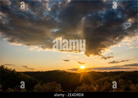 Il sole tramonta mentre si avvicinano le nuvole scure. Foto Stock