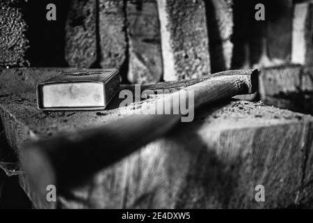 Immagine in scala di grigi di un'ascia con manico in legno e. scatola di accoppiamento di sicurezza su una superficie con segatura Foto Stock