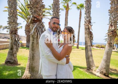 La coppia appena sposata è felice dopo essersi sposata, stanno celebrando la luna di miele in una posizione tropicale a Tenerife. Foto Stock