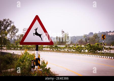 Cartello stradale indiano che indica l'attraversamento di cervi. Cartello che indica di prestare attenzione alla fauna selvatica come i cervi mentre la strada passa attraverso la riserva forestale Foto Stock