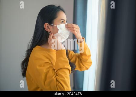 Una giovane bella donna che indossa una maschera facciale protettiva per prepararsi ad uscire, Healthcare e covid-19 Concept Foto Stock