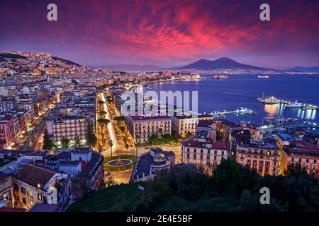 Napoli, tramonto viola rosa sera crepuscolo. Città Napoli in Italia, viaggiare in Europa. Paesaggio urbano con città, mare, colline e Vulcano Vesuvio Foto Stock