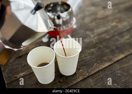 Uomo viaggiatore che versa caffè caldo fresco dalla macchina del caffè geyser in una tazza all'aperto, passo dopo passo, attività di viaggio per rilassarsi, bushcraft, avventura, tra Foto Stock