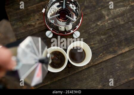 Uomo viaggiatore che versa caffè caldo fresco dalla macchina del caffè geyser in una tazza all'aperto, passo dopo passo, attività di viaggio per rilassarsi, bushcraft, avventura, tra Foto Stock