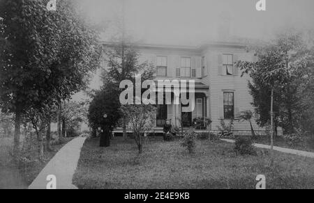 Archivio americano foto monocromatica di una grande casa di ciottoli con due donne fuori del giardino anteriore. Preso nel tardo 19 ° secolo a Port Byron, New York, Stati Uniti Foto Stock