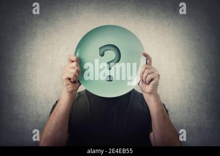 L'uomo anonimo nasconde la sua identità, coprendo il viso utilizzando un piatto vuoto con punto interrogativo. Crisi globale, problema di approvvigionamento alimentare. Messaggio concettuale, Foto Stock
