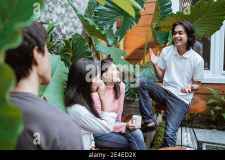 Gruppo di amici allegri mentre si è seduti e chiacchierando con un cortile Foto Stock