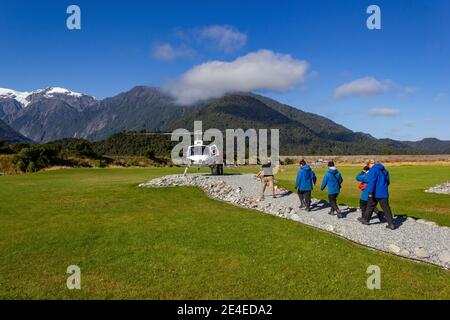 Franz Josef, Nuova Zelanda - 22 febbraio 2016: Un gruppo di turisti che camminano verso un elicottero sul ghiacciaio Franz Josef Foto Stock