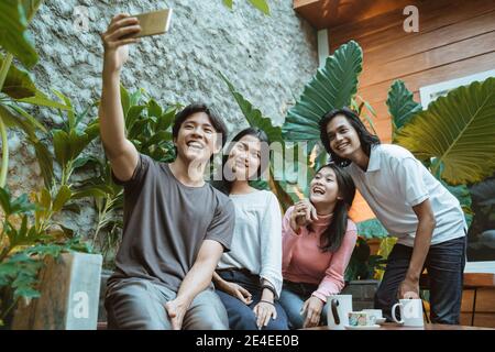 Gruppo di persone sorridenti felici che prendono un autoritratto in un caffetteria all'aperto Foto Stock