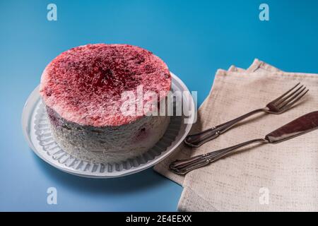 Panna di Spagna al lampone a basso contenuto calorico con gelatina, panna montata e frutti di bosco freschi e stoviglie su sfondo blu. La vista dall'alto. Foto Stock