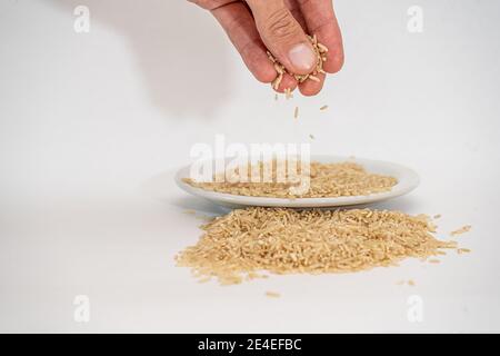 Versare il riso su un mucchio isolato su un superficie bianca Foto Stock