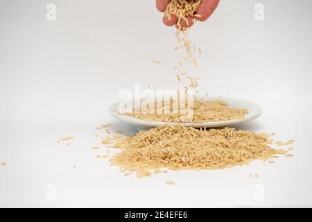 Versare il riso su un mucchio isolato su un superficie bianca Foto Stock